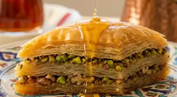 Delizioso baklava ricetta con strati di pasta fillo, pistacchi e noci, inzuppato in sciroppo dorato.