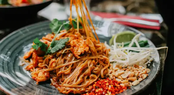 Pyszny pad thai z kurczakiem, orzeszkami, kiełkami i limonką. Tak jemy pad thai, dodając przyprawy do smaku.
