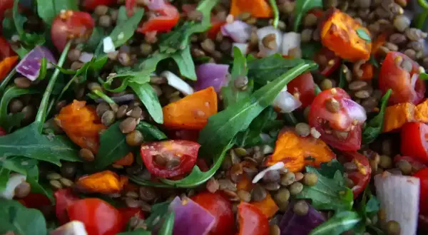 Salade colorée de lentilles vertes, tomates cerises, oignons rouges et roquette. Un plat sain et savoureux.