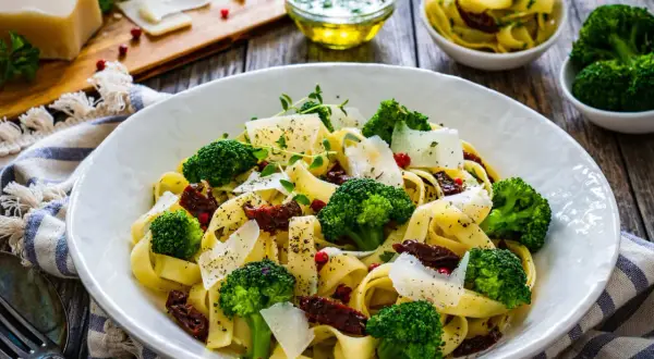 Pyszny obiad z brokułem: tagliatelle z zielonymi różyczkami, suszonymi pomidorami i parmezanem.