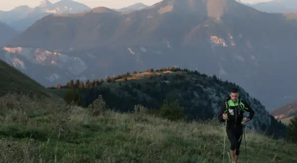 Un coureur en plein effort, bâtons en main, sur un sentier de montagne. Un aperçu de son plan d'entraînement UTMB.
