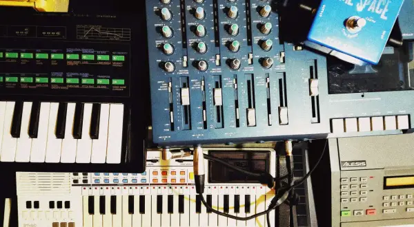 A musician's setup with keyboards, a mixer, and a blue "Time Space" pedal. This image shows how to clear sample data from a synthesizer.