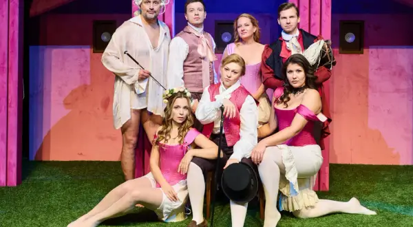Aktorzy w strojach teatralnych, którzy pracują w teatrze, pozują na scenie.
