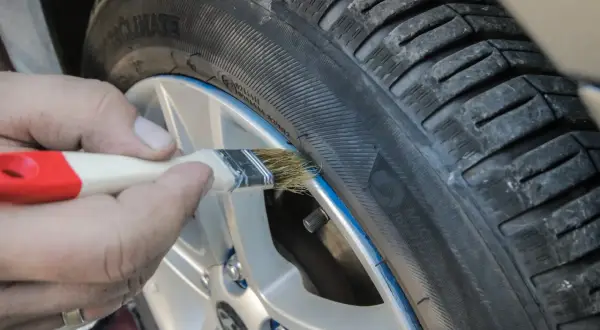 Ręczne malowanie felgi pędzlem, pokazujące zastosowanie gumy w sprayu do tuningu wizualnego opon.