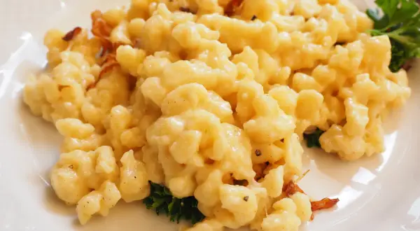 Gnocchetti di patate conditi con formaggio fuso e speck croccante, un classico dei primi piatti trentini.