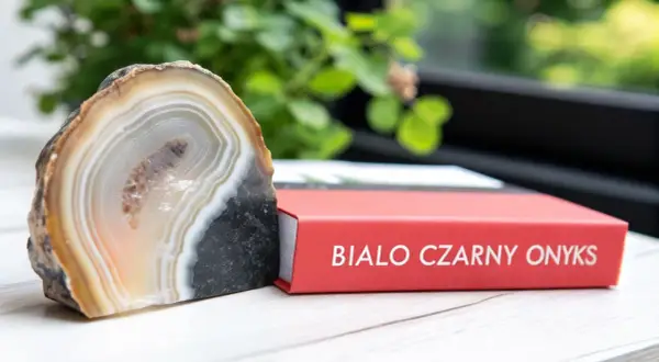Onyks dla jakiego znaku zodiaku? Piękny, pasiaste agat obok czerwonej książki z napisem "Biało Czarny Onyks".