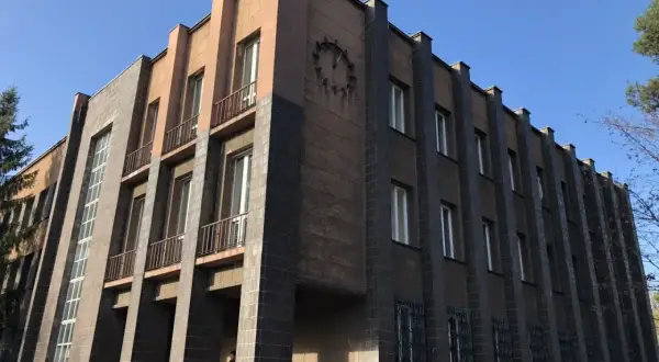 Monumentalny budynek z zegarem, przykład art deco w Polsce. Geometryczne formy, ciemna i jasna elewacja, wąskie okna.