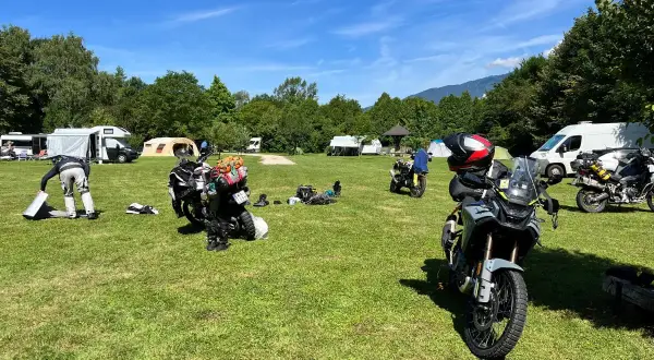 Motocykle zaparkowane na kempingu, w tle namioty i kampery.