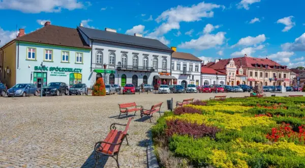 Kolorowy rynek z ławkami i kwitnącymi rabatami, idealne miejsce na tanie wycieczki 3 dniowe.