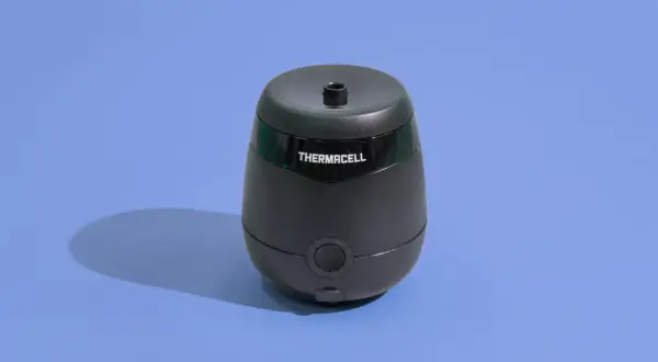 Czarny odstraszacz Thermacell na niebieskim tle. Zapewnia strefę wolną od kleszczy, chroniąc ludzi.