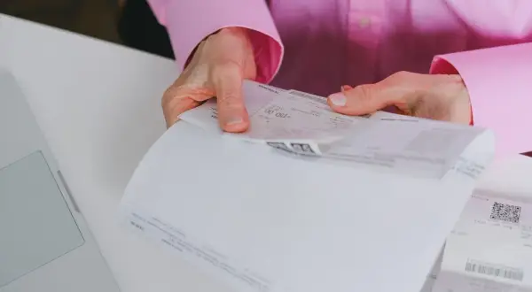 Dłonie trzymają dokumenty, na jednym z nich widnieje kwota 150,00 zł. To może być faktura uproszczona.