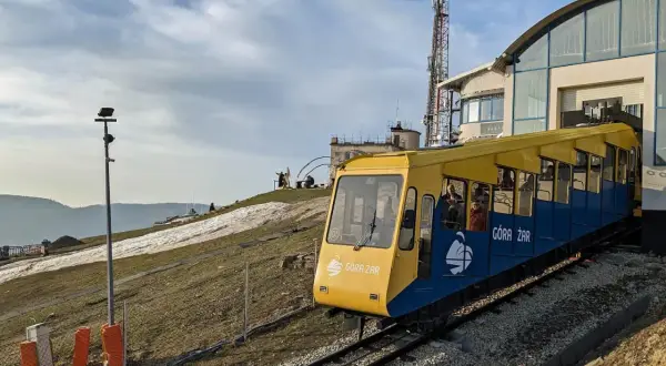 Kolejka linowo-terenowa Góra Żar wjeżdża na szczyt. Widok na trasę i budynek stacji.