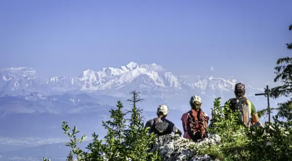 Trois randonneurs contemplent les sommets enneigés après une randonnée dans le Jura.