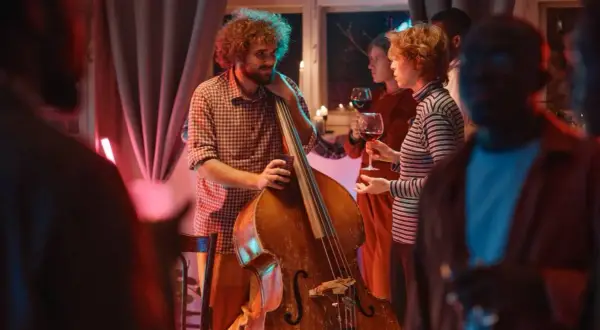 Muzyk z kontrabasem i goście z winem. Idealny strój na koncert jazzowy to swobodna elegancja.