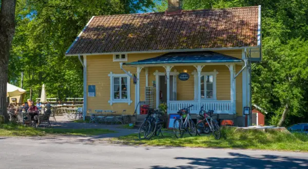 Gult hus med café & vandrarhem. Cyklar står parkerade framför. Folk sitter vid bord utomhus.