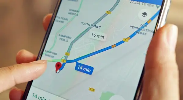 Palec wskazuje na mapę na ekranie telefonu, pokazując trasę i czas dojazdu. Dowiedz się, jak wysłać pinezkę, by udostępnić lokalizację.
