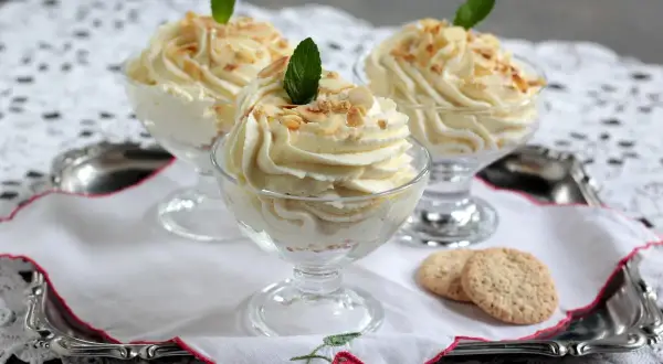 Cremige Desserts in Gläsern, garniert mit Mandelsplittern und Minze. Ein Hauch von Zitrone, wie bei einem feinen lemon curd, macht sie unwiderstehlich.