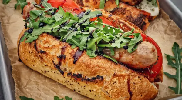 Ein knuspriges Baguette mit einer herzhaften salsiccia italiana, frischen Tomaten und Rucola, beträufelt mit Balsamico.