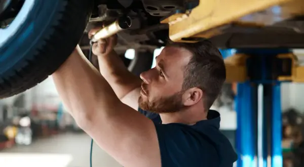 Mechanik sprawdza podwozie auta. Dowiedz się, ile kosztuje przegląd samochodu z gazem.