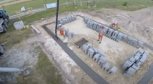 Budowa fundamentów: betonowanie i układanie bloczków przez robotników.