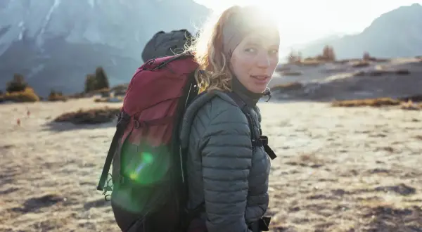 Kobieta z plecakiem w górach, gotowa na przygodę. To prawdziwy backpacking po polsku, z widokiem na majestatyczne szczyty.