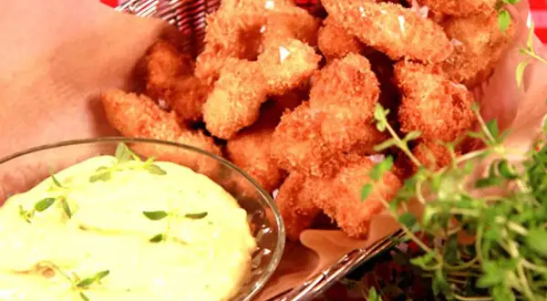 Korg med gyllene chicken nuggets, serverade med en krämig dipp och färska örter.