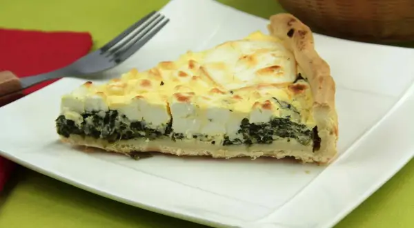 Rebanada de quiche de espinacas con queso feta y una corteza dorada, lista para ser disfrutada.