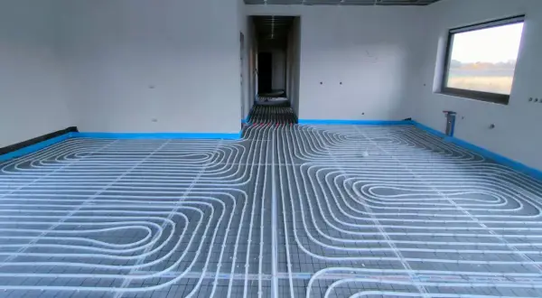 Instalacja ogrzewania podłogowego w nowym domu. Rury ułożone na siatce, gotowe do zalania betonem. To przyszłe oszczędności na koszt ogrzewania podłogowego.