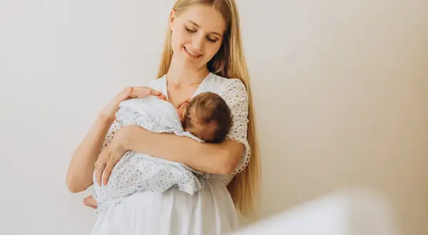 Szczęśliwa mama z niemowlęciem na rękach. To piękny okres karmienia piersią, pełen bliskości i miłości.