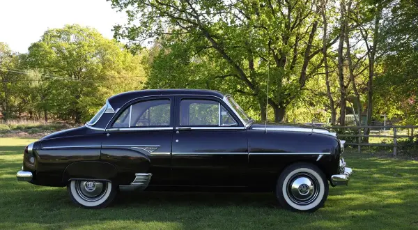 Svart Vauxhall Cresta parkerad på en gräsmatta med träd i bakgrunden.