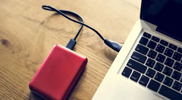 Czerwony dysk zewnętrzny podłączony do laptopa. Komputer nie widzi dysku zewnętrznego, co może być frustrujące.