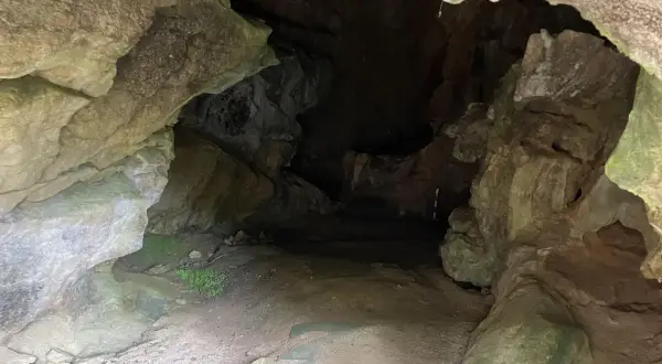 Entrada a la cueva de la Loja, con rocas irregulares y un camino de tierra que se adentra en la oscuridad.