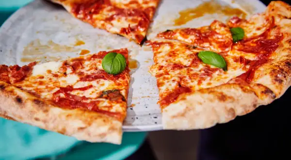 Une pizza diabola appétissante, avec sa croûte dorée, sa sauce tomate épicée et son fromage fondant, garnie de feuilles de basilic frais.