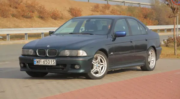 Ciemnozielone BMW E39 z polskimi tablicami WF 65015 stoi na parkingu.