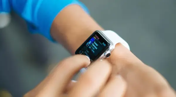 Une personne utilise sa montre connectée pour vérifier des informations. Peut-on téléphoner avec une montre connectée ? Oui, certaines le permettent.
