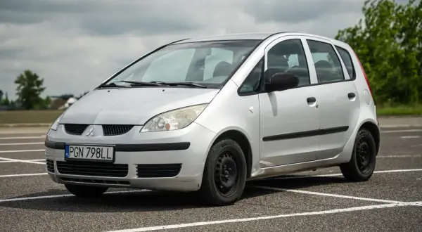 Srebrny Mitsubishi Colt z tablicą rejestracyjną PGN 798LL stoi na parkingu.