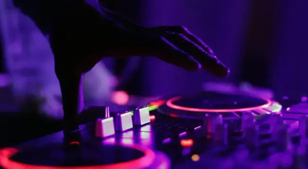 Dłoń DJ-a nad konsolą, czerwone i fioletowe światła. Czy to ZAIKS co to za muzyka?