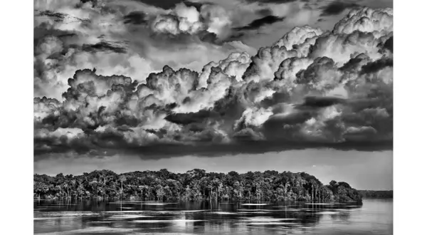 Dramatyczne chmury nad Amazonką, uchwycone przez Sebastiao Salgado. Potężna rzeka i bujna dżungla.
