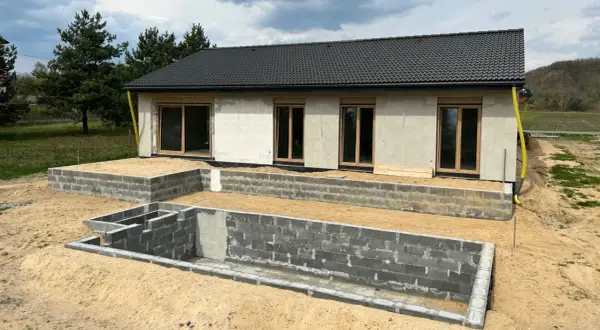 Budowa domu w 3 forma build. Fundamenty z bloczków betonowych, ściany z betonu komórkowego, dach pokryty dachówką.
