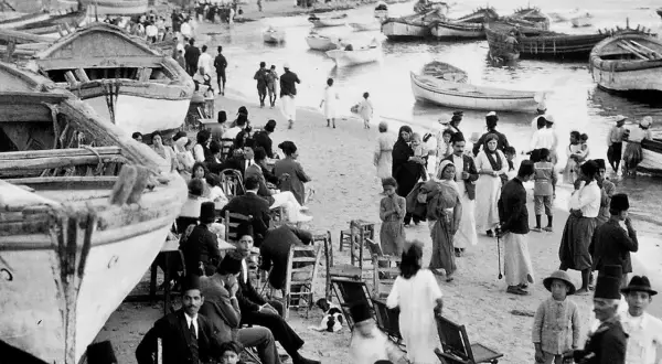 Gente en la playa con barcos, un vistazo al posible origen del conflicto entre Israel y Palestina.