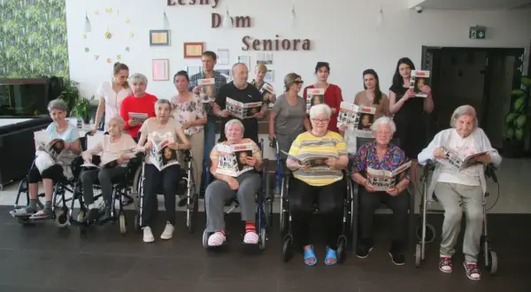 Grupa seniorów z czasopismami w leśnym domu seniora.