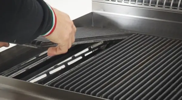 Mano che posiziona le pietre laviche nel barbecue a gas, pronte per una grigliata perfetta.