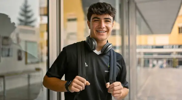 Ung kille med hörlurar och ryggsäck, redo för en **rig fotboll**-träning.