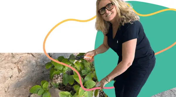 Une femme souriante jardine, un exemple de loisirs pour jeunes retraités actifs et épanouis.