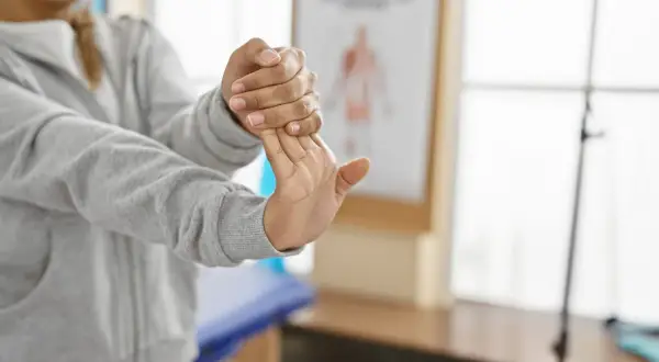 Person stretchar handleden för musarm behandling.