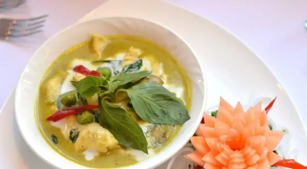 Zielony curry z kurczakiem, mleczkiem kokosowym i bazylią. Czy przyprawa curry jest ostra? Ten talerz sugeruje, że tak, dzięki czerwonym papryczkom chili.