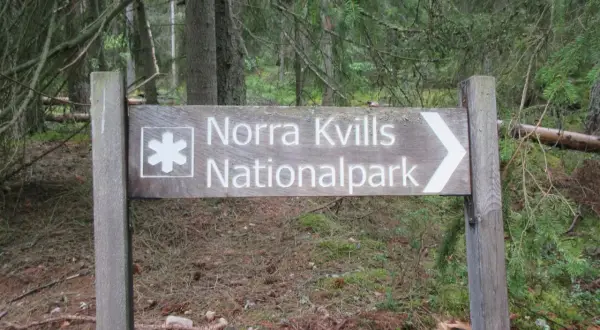 Skylt visar vägen till Norra Kvills Nationalpark genom en tät skog.