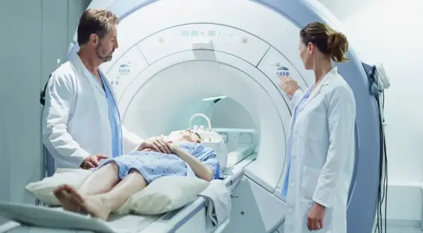 Pacjentka leży w aparacie do rezonansu magnetycznego, a lekarze przygotowują badanie z kontrastem.