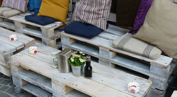 Un accogliente divano fai da te realizzato con pallet, decorato con cuscini colorati e un tavolino, perfetto per un angolo relax.