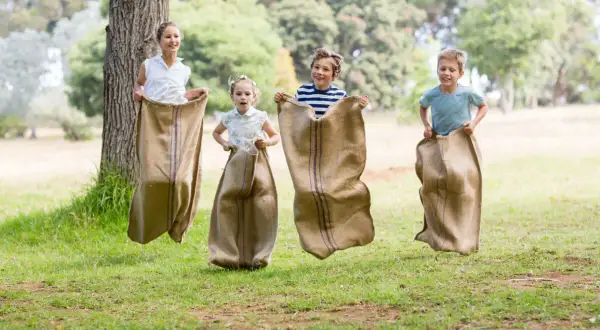 Niños compiten en una divertida carrera de sacos en un día soleado en el parque.